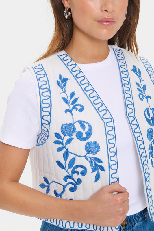 Sleeveless vest in off-white with blue floral embroidery at the front. Open front, straight cut, and cropped length. A decorative and lightweight layer – ideal over a tee or dress.

Fit: fit
Fabric 100% Cotton
Colour: White

The Beach House Boutique, Rock, Cornwall.

