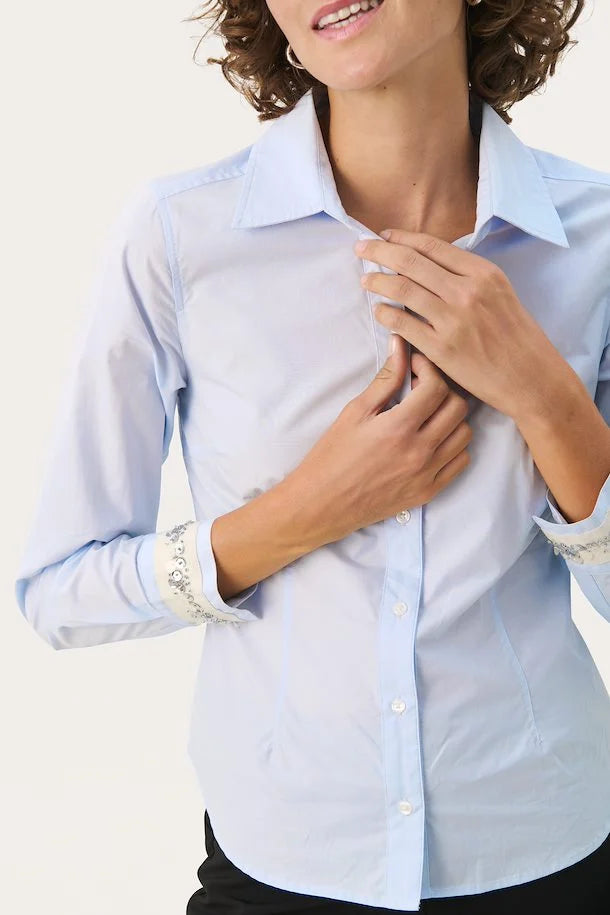 This classic blue shirt gets a modern twist with elegant sequins on the sleeves, adding a touch of glamour. The shirt is designed with a flattering fit and a classic collar, making it perfect for both formal and casual occasions.

Fit: Regular fit
Length: 59.5 cm corresponds to size 34
Composition : 100% Cotton

Colour: Plein Air
The Beach House Boutique, Rock, Cornwall. 